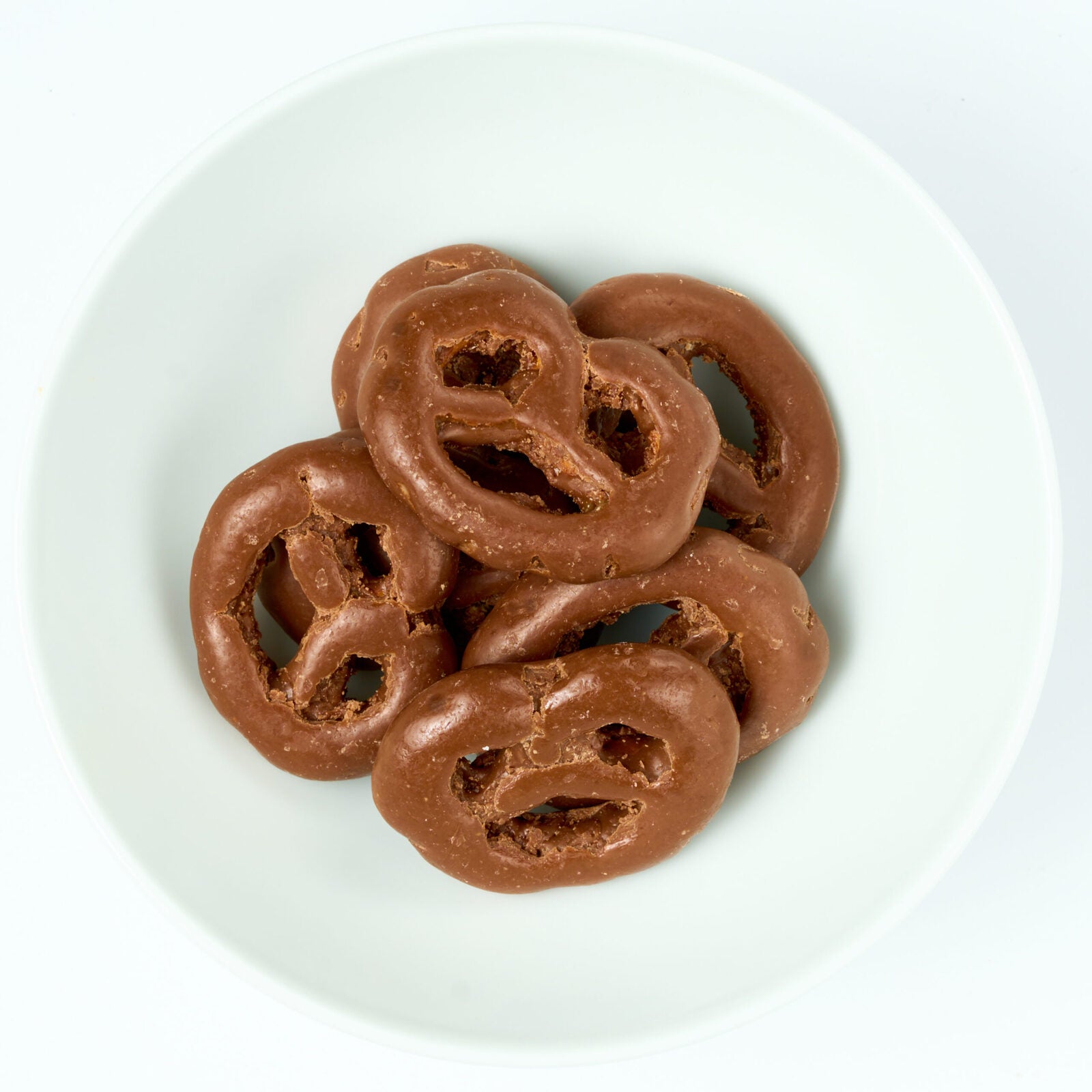 Bite-size pretzels fully dipped in smooth milk chocolate, plated on white.