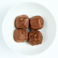 Milk chocolate covered caramel candies, square chocolate-coated pieces, arranged on a white round plate.