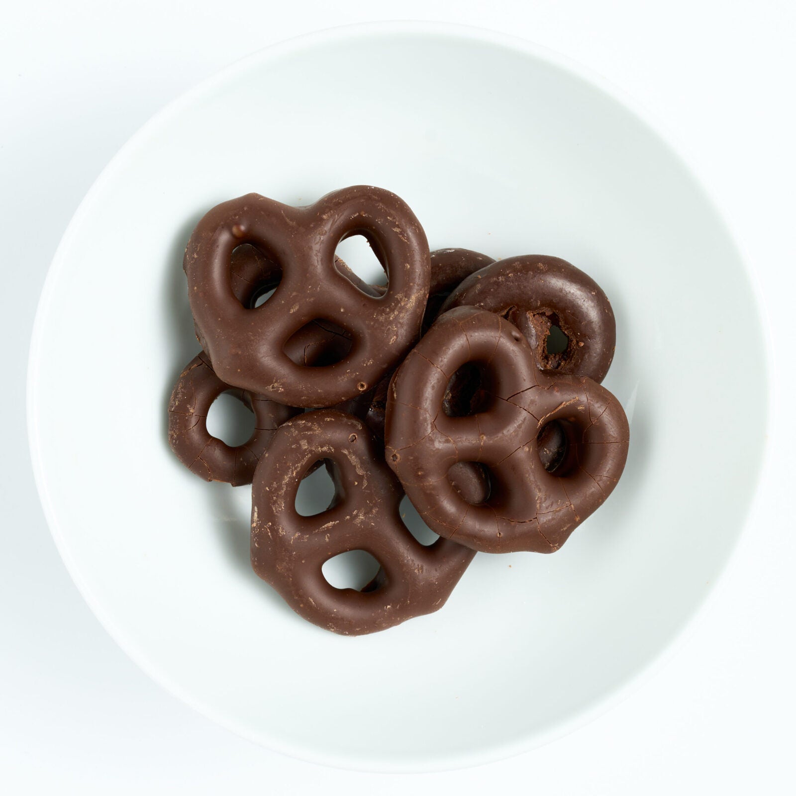 Bite-size pretzels fully dipped in smooth dark chocolate, plated on white.