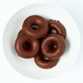 Ring-shaped jelly candies fully coated in dark chocolate, piled on a white plate.