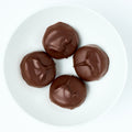 Round dark chocolate covered thin mint patties with smooth shiny coating, plated on white.